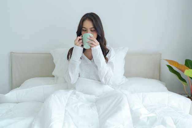 Belle fille assise et buvant du thé chaud le matin