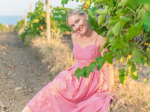 Belle fille assise dans un vignoble vêtue d'une robe de pin-up rouge