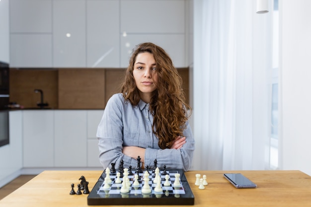 Belle fille assise à la maison et jouer aux échecs