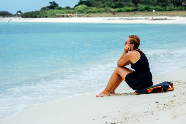 Belle fille assise pensivement sur la plage