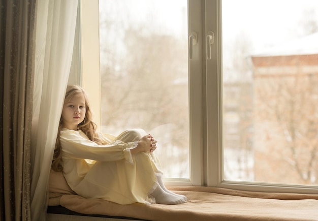 Belle fille assise sur le rebord de la fenêtre