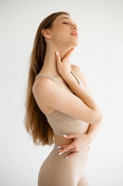 Belle fille athlétique en vêtements de fitness en studio sur fond blanc