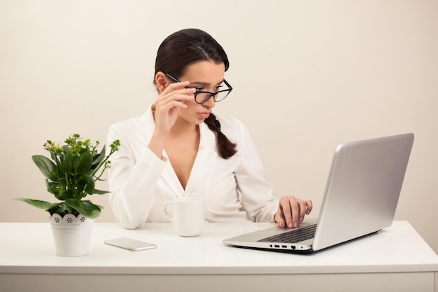 Belle fille au bureau travaillant sur l'ordinateur