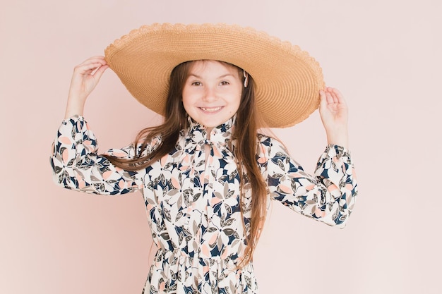 Belle fille au chapeau sur fond rose