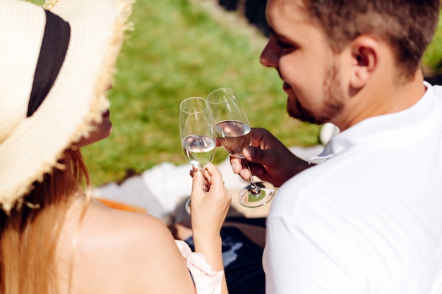 Belle fille au chapeau de paille communique avec le jeune homme attrayant et boit du vin