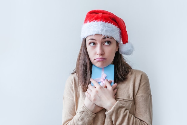 Belle fille au chapeau de père Noël rouge tenant une boîte cadeau bleue à la main