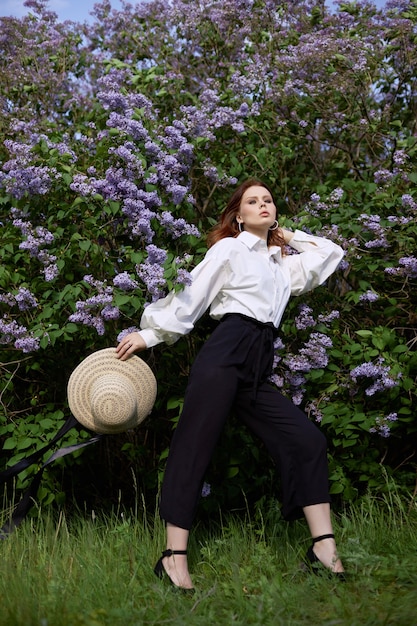 Belle fille au printemps dans les branches des buissons de lilas fleuris Portrait d'une femme par un beau jour d'été