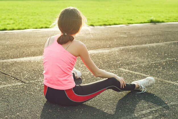 Belle fille au repos après l'entraînement au stade