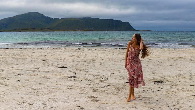 belle fille aux cheveux longs dans une robe se promène le long de la célèbre plage de ramberg (rambergstranda), norvège