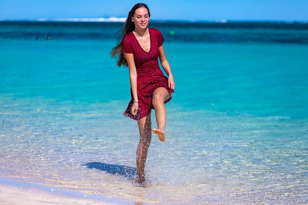 belle fille aux cheveux longs dans une robe trempe ses pieds dans l'eau dans la baie turquoise de l'ouest de l'australie