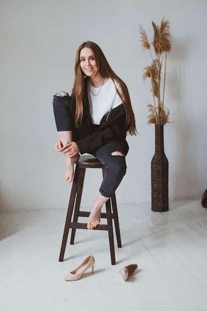 Belle fille aux cheveux longs est assise sur une chaise dans une belle pièce et pose pour une photo