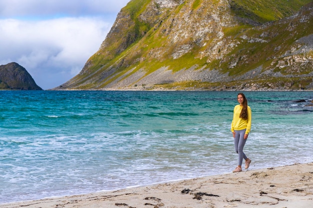 une belle fille aux cheveux longs profite du beau temps sur la célèbre plage paradisiaque haukland, norvège