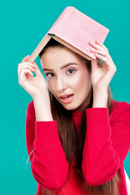 belle fille aux cheveux longs en pull rouge lit le livre