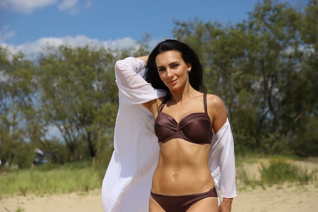 Belle fille aux cheveux noirs en maillot de bain sur la plage