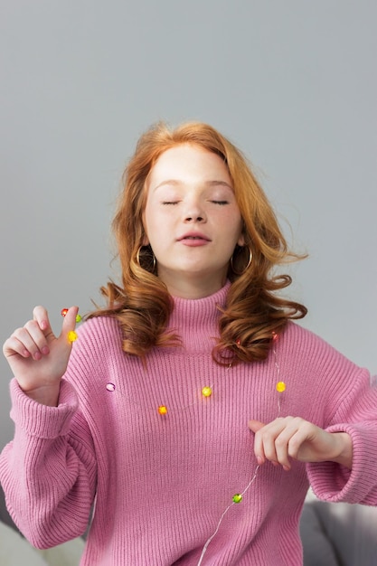 Belle fille aux cheveux rouges tient une guirlande multicolore près du corps. Ambiance et ambiance de Noël