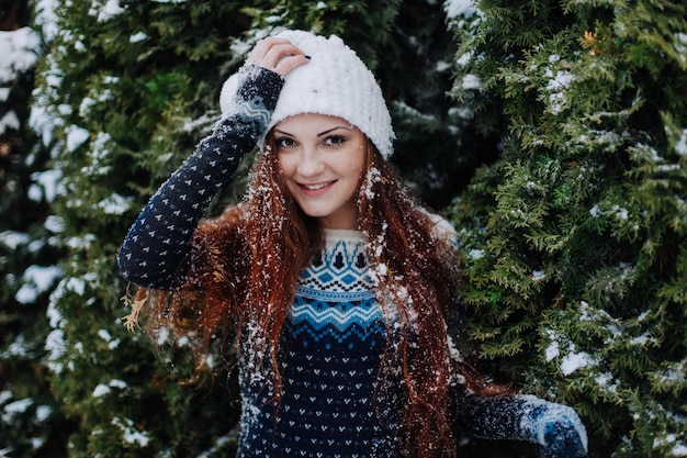 Belle fille aux cheveux roux dans un parc d'hiver avec de la neige