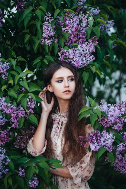 Belle fille aux grands yeux près de l'arbre de lilas.