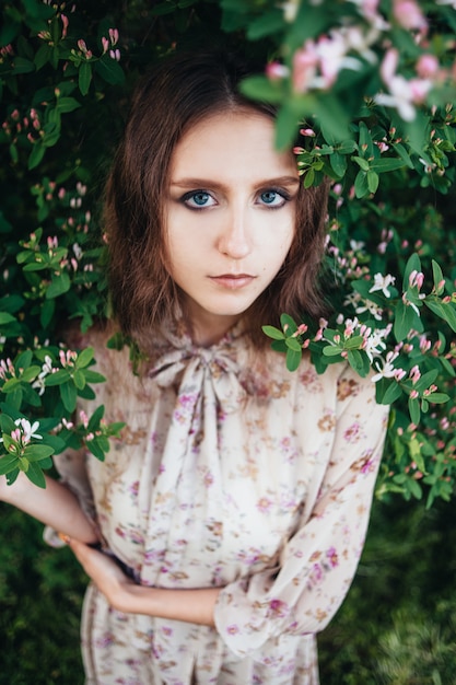 Belle fille aux grands yeux près de l'arbre de lilas.