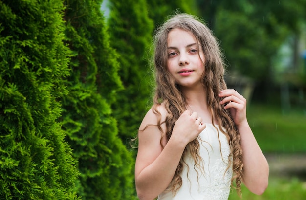 Belle fille aux longs cheveux bouclés portant une robe blanche tendresse et concept de jeunesse