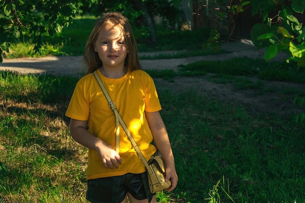 une belle fille aux longs cheveux roux dans des vêtements jaune vif se tient sous un arbre en été