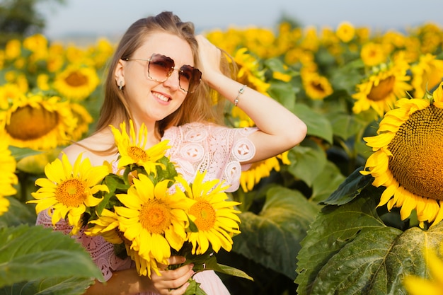 Belle fille aux tournesols au coucher du soleil