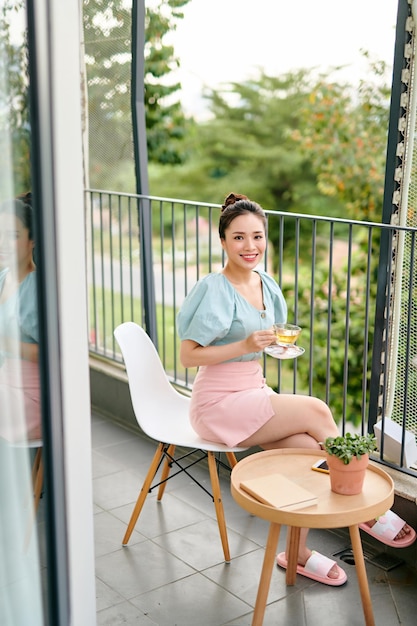 Belle fille sur le balcon en train de boire du thé