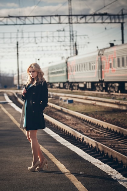 Belle fille blonde attend le train à la gare. look romantique et délicat