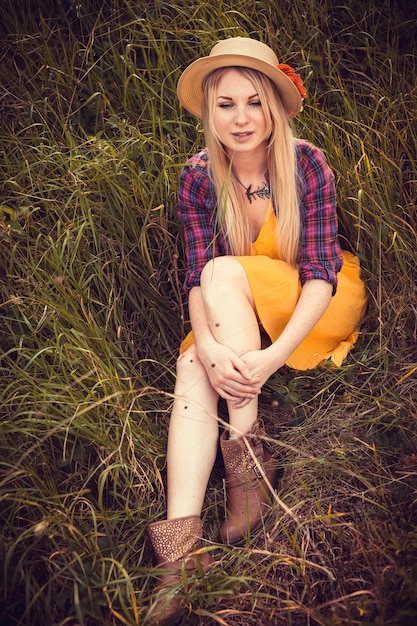 Belle fille blonde au chapeau, chemise à carreaux et robe dans la nature