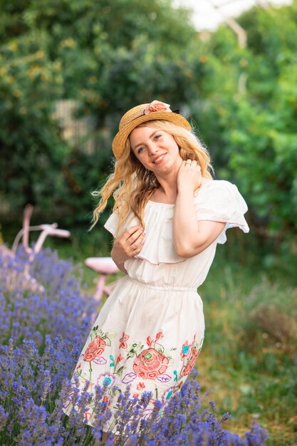 Belle fille blonde au chapeau près des buissons de lavande