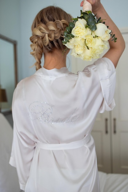 Belle fille blonde aux cheveux tressés en robe de chambre blanche