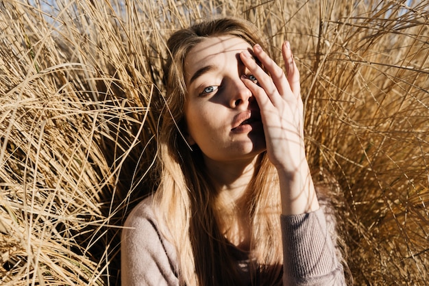 Belle fille blonde aux yeux bleus modèle posant au soleil, à l'extérieur