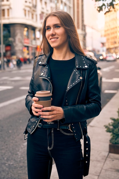 Belle fille blonde avec un café souriant dans la rue