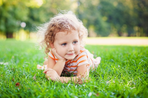 Belle fille blonde curle dehors dans un champ avec la lumière du soleil sur ses cheveux