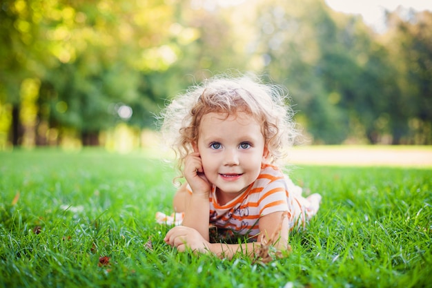 Belle fille blonde curle dehors dans un champ avec la lumière du soleil sur ses cheveux