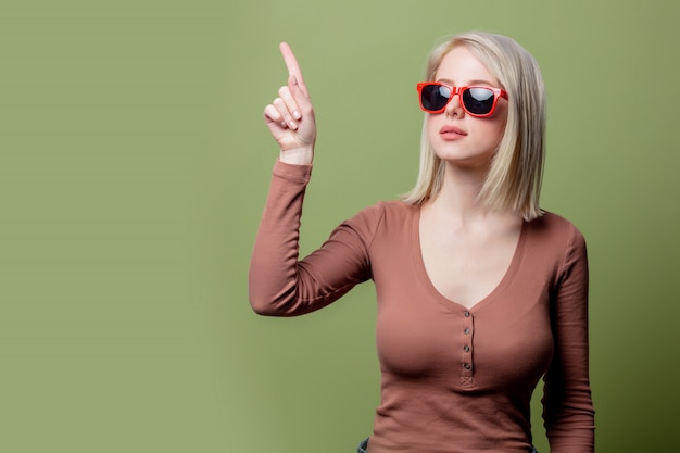 Belle fille blonde dans des lunettes de soleil et un chemisier