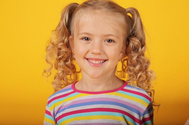 belle fille blonde heureuse souriante sur fond jaune dans une veste colorée