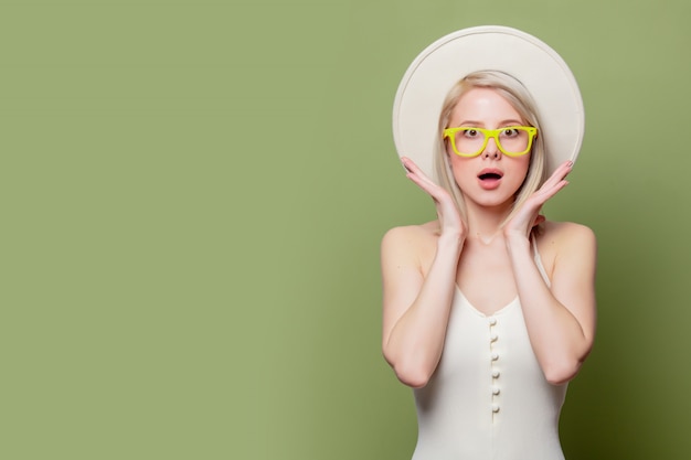 Belle fille blonde à lunettes et chapeau blanc