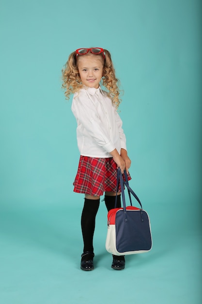 belle fille blonde avec des lunettes dans une jupe chemise une écolière avec une mallette