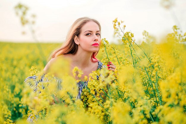 Belle fille blonde pose pour la caméra dans le champ de colza