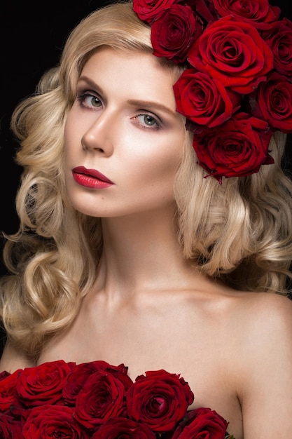 Belle fille blonde en robe et chapeau avec roses, maquillage classique, boucles, lèvres rouges. Beau visage.