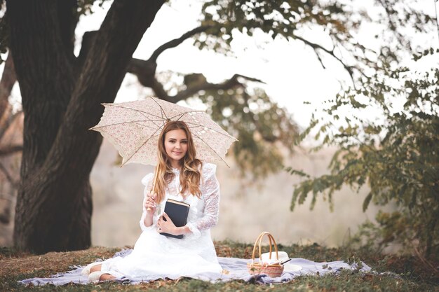 Belle fille blonde tenant un livre en papier et un parapluie vintage