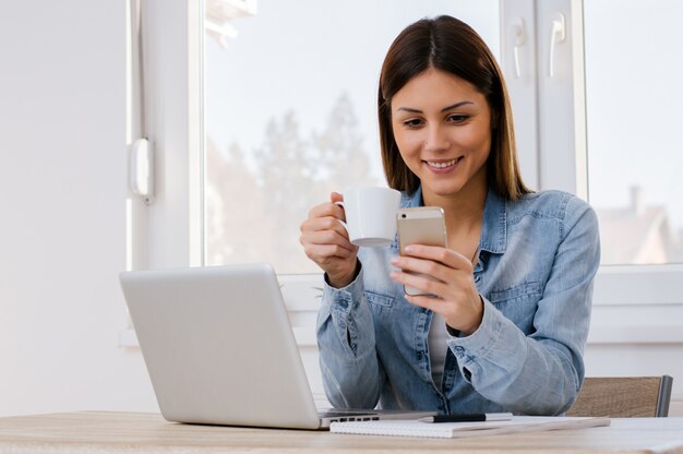 Belle fille boire du café et envoyer des SMS à son petit ami