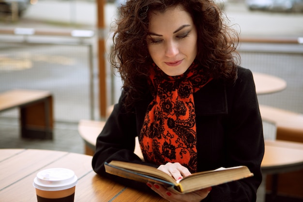 Belle fille, boire du café et lire un livre