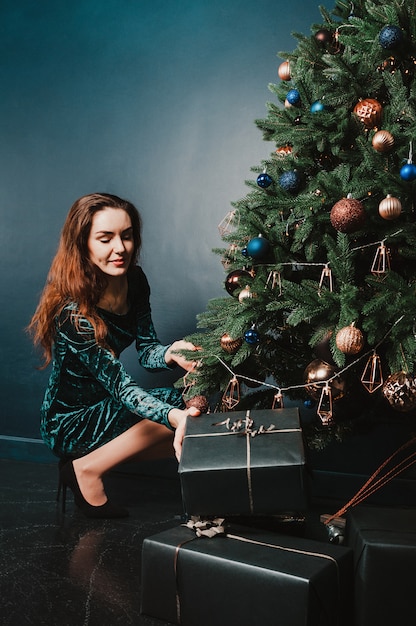 Belle fille avec une boîte cadeau près de sapin de Noël pour poster