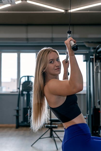 Belle fille en bonne santé avec des trains de figures sportives dans la salle de gym Entraînement des muscles du dos Poussée du bloc supérieur