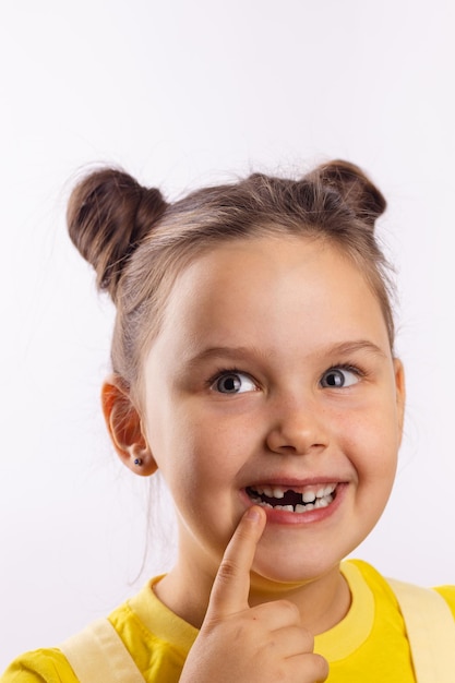 Belle fille avec la bouche ouverte montrant la dent de lait avant manquante avec le doigt sur la lèvre inférieure souriant ...