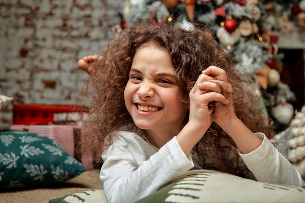 Belle fille avec des boucles dans le contexte des décorations de Noël