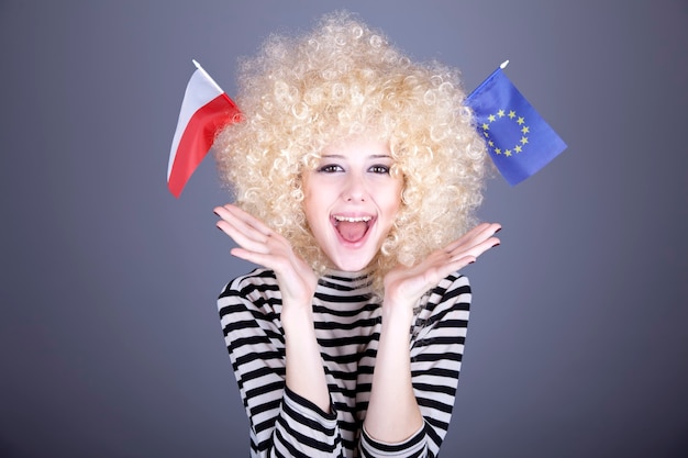 Belle fille avec des boucles montrent le drapeau de l'Union européenne et de la Pologne.