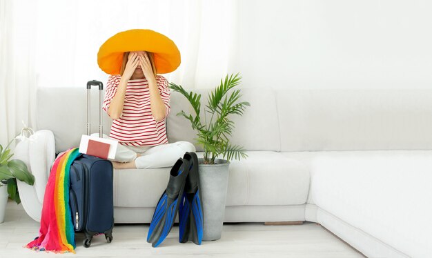 Belle fille bouleversée dans un chapeau jaune reste à la maison et prévoit un voyage en vacances. En attente de voyage.