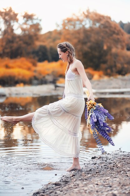 Belle fille avec un bouquet de fleurs bleues sur la nature en automne